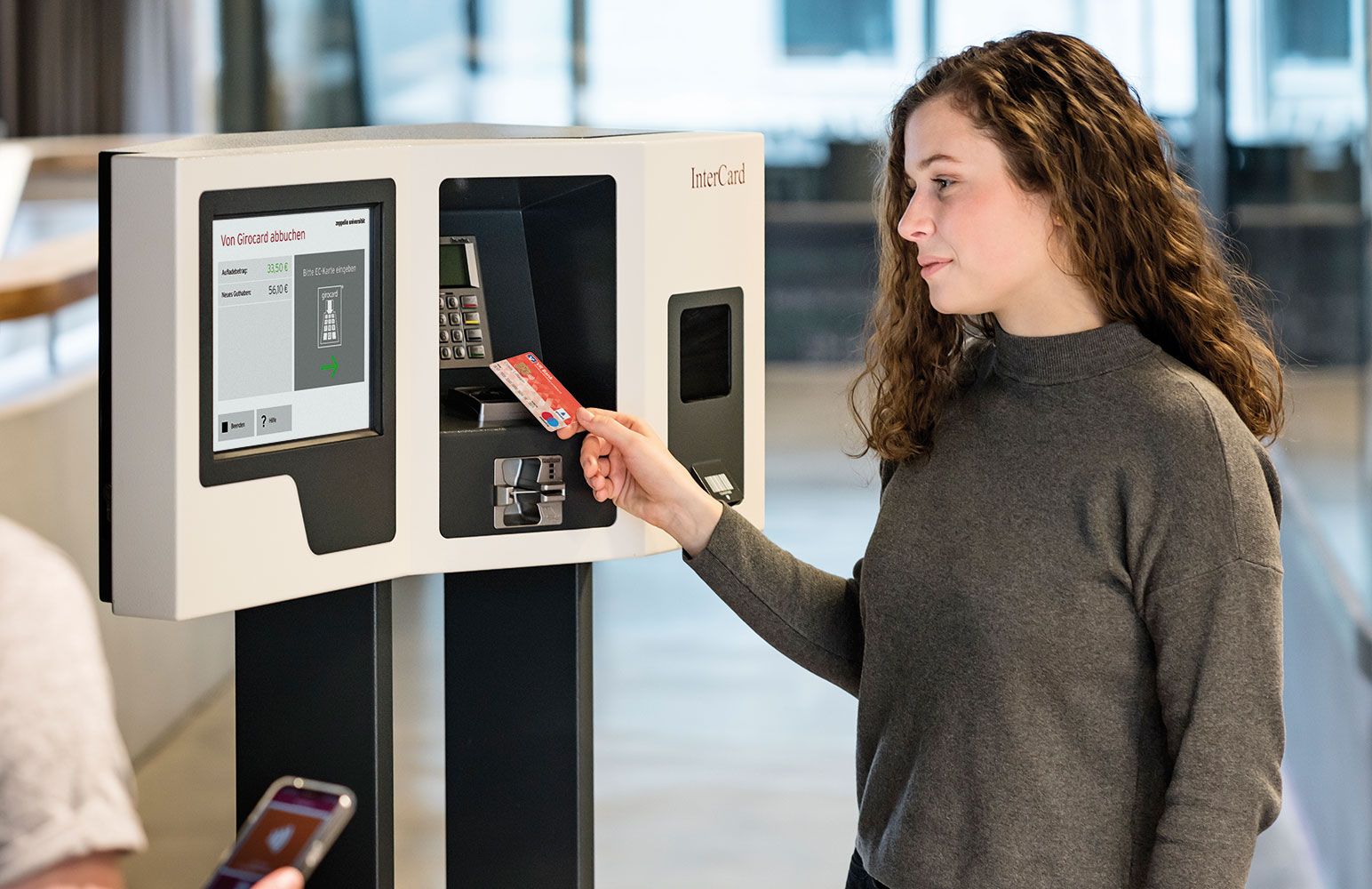 Studentin lädt Guthaben am Aufladeautomaten smartUP auf ihre Chipkarte